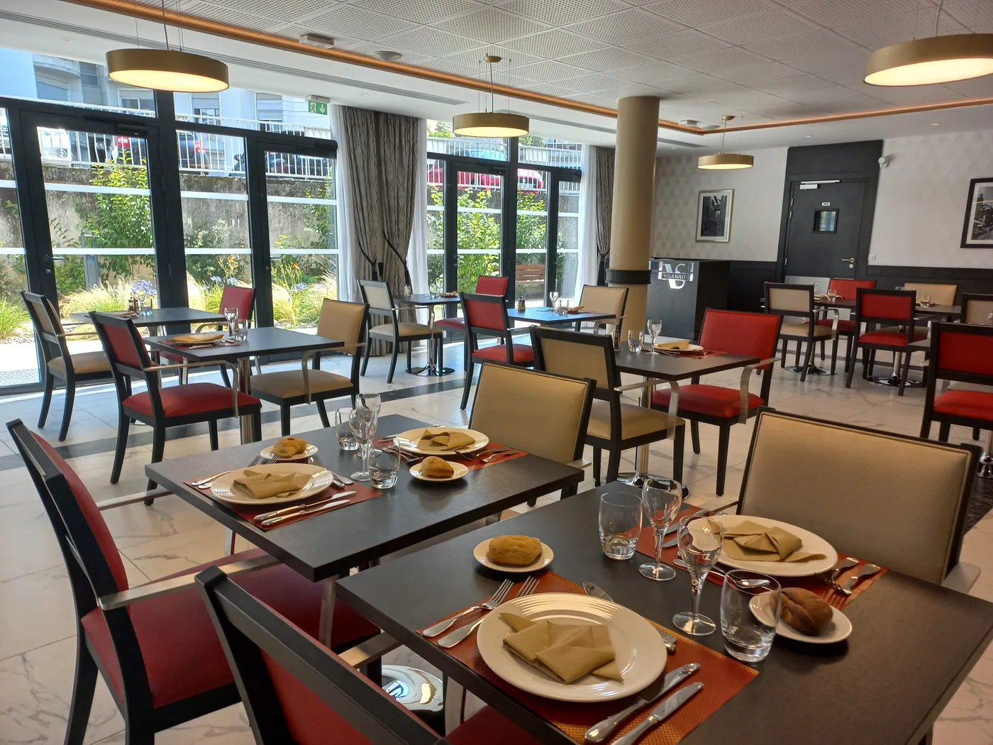 Bright restaurant dining room at the OBEO senior residence in Chambéry, with set tables facing floor-to-ceiling windows overlooking the garden