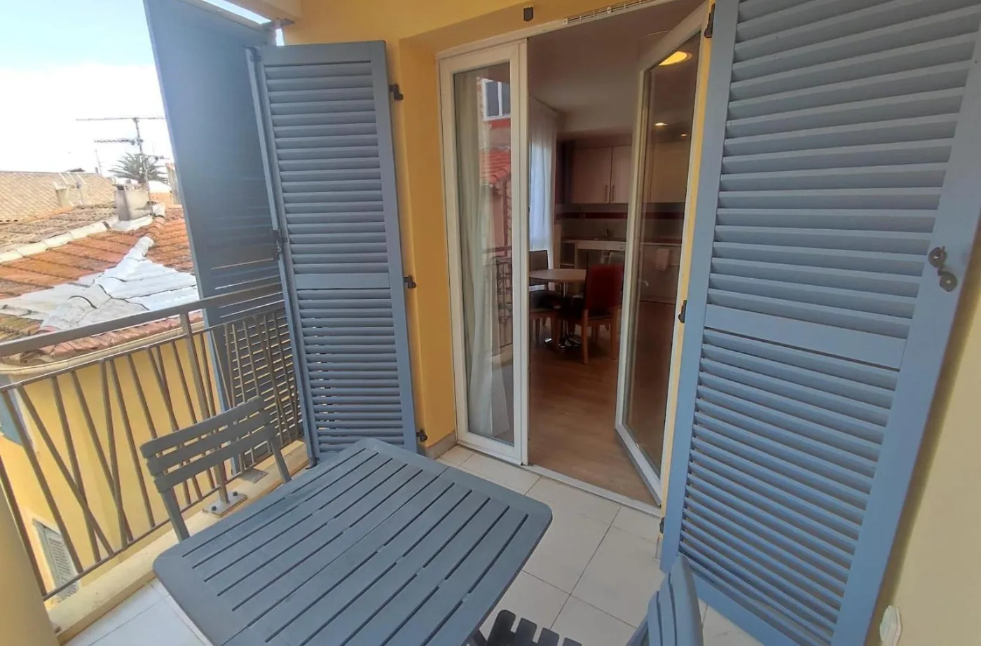 Balcon d’un appartement de Fréjus, volets provençaux ouverts sur les toits de tuiles du centre historique