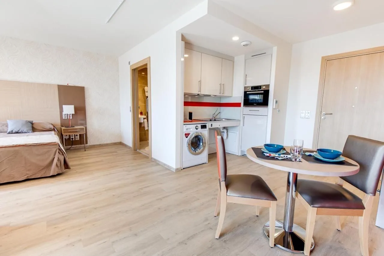 Appartement témoin de Fréjus : table de repas dressée, kitchenette équipée avec lave-linge et espace nuit en enfilade