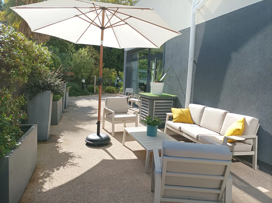 Terrasse extérieure d'une résidence OBEO avec salon de jardin et parasol
