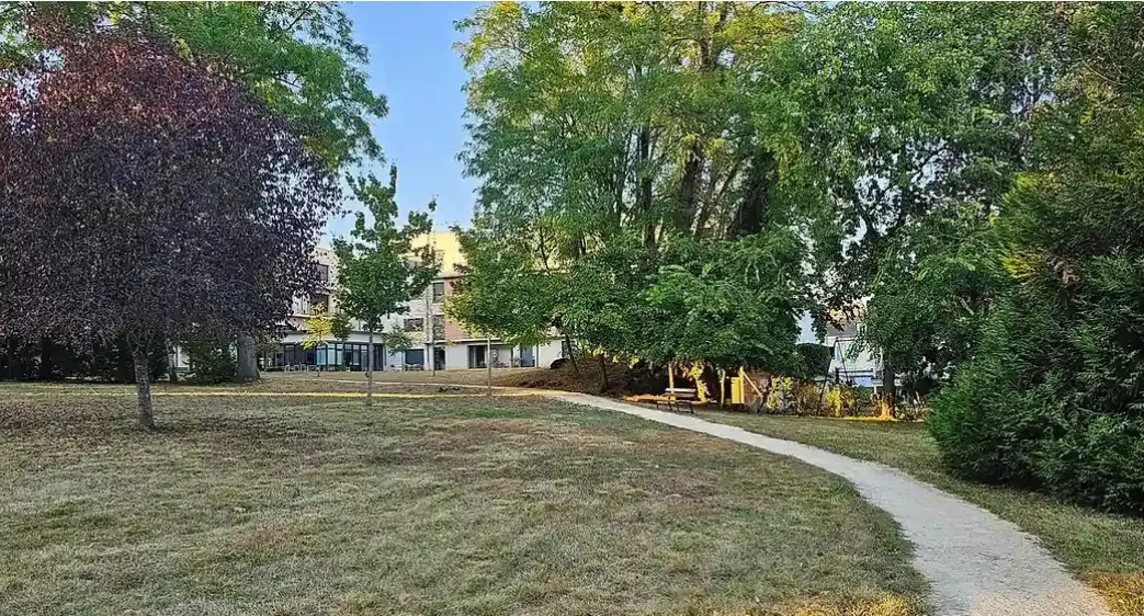 Parc extérieur d'une résidence OBEO avec pelouse et allée piétonne