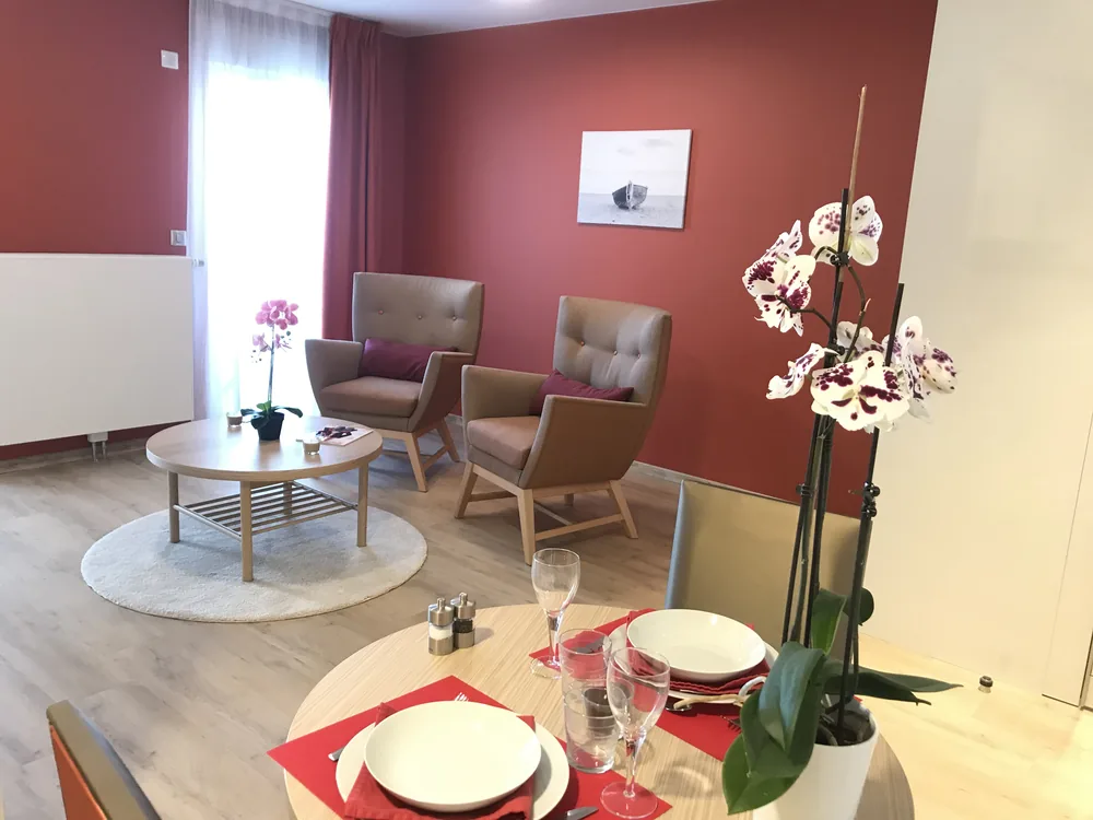 Séjour lumineux d'un appartement de la résidence OBEO Montreuil, avec murs terracotta et fauteuils