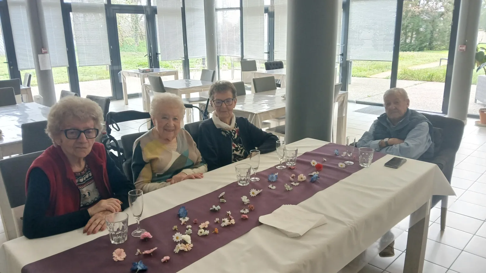 Résidents attablés dans la salle à manger décorée de fleurs à la résidence OBEO Nevers
