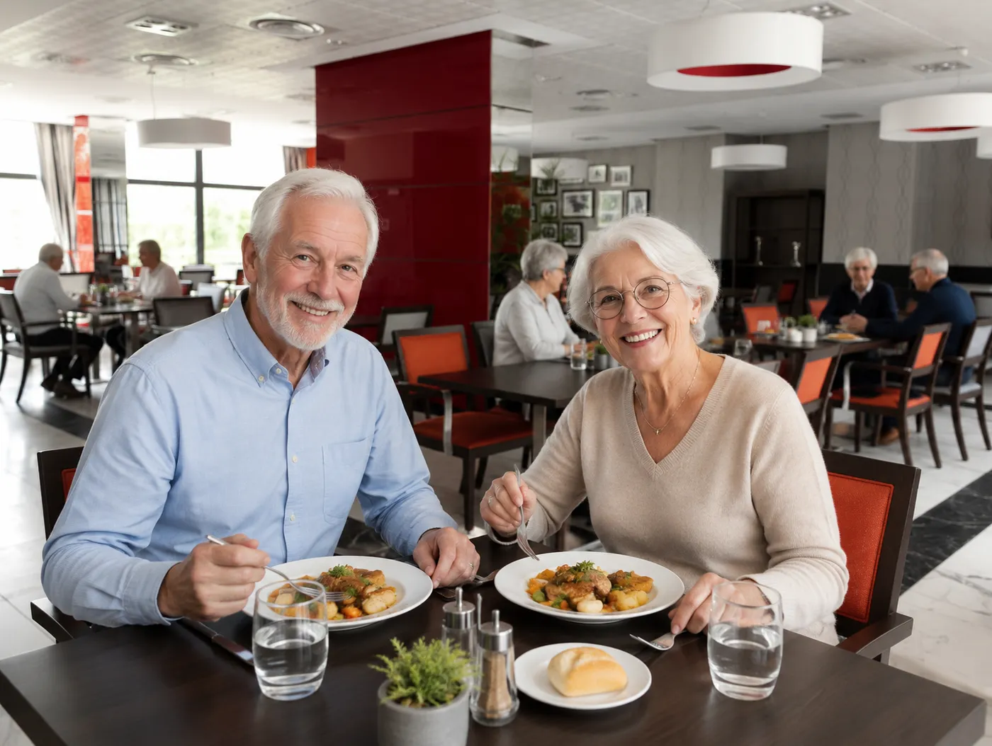 Un couple de seniors savoure son assiette à une table du restaurant de la résidence