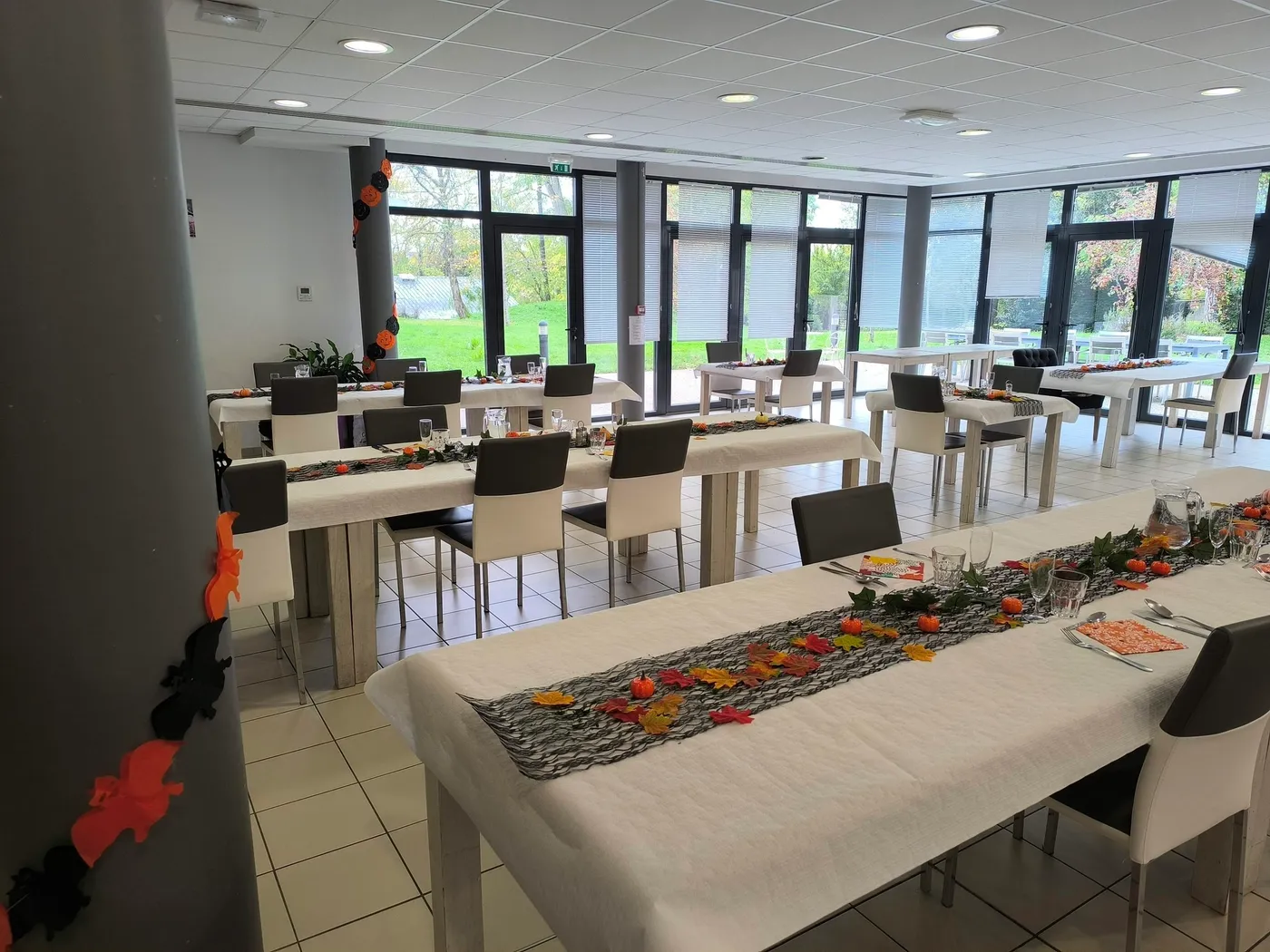 La salle à manger parée de feuilles d'automne et de décorations d'Halloween le long des tables