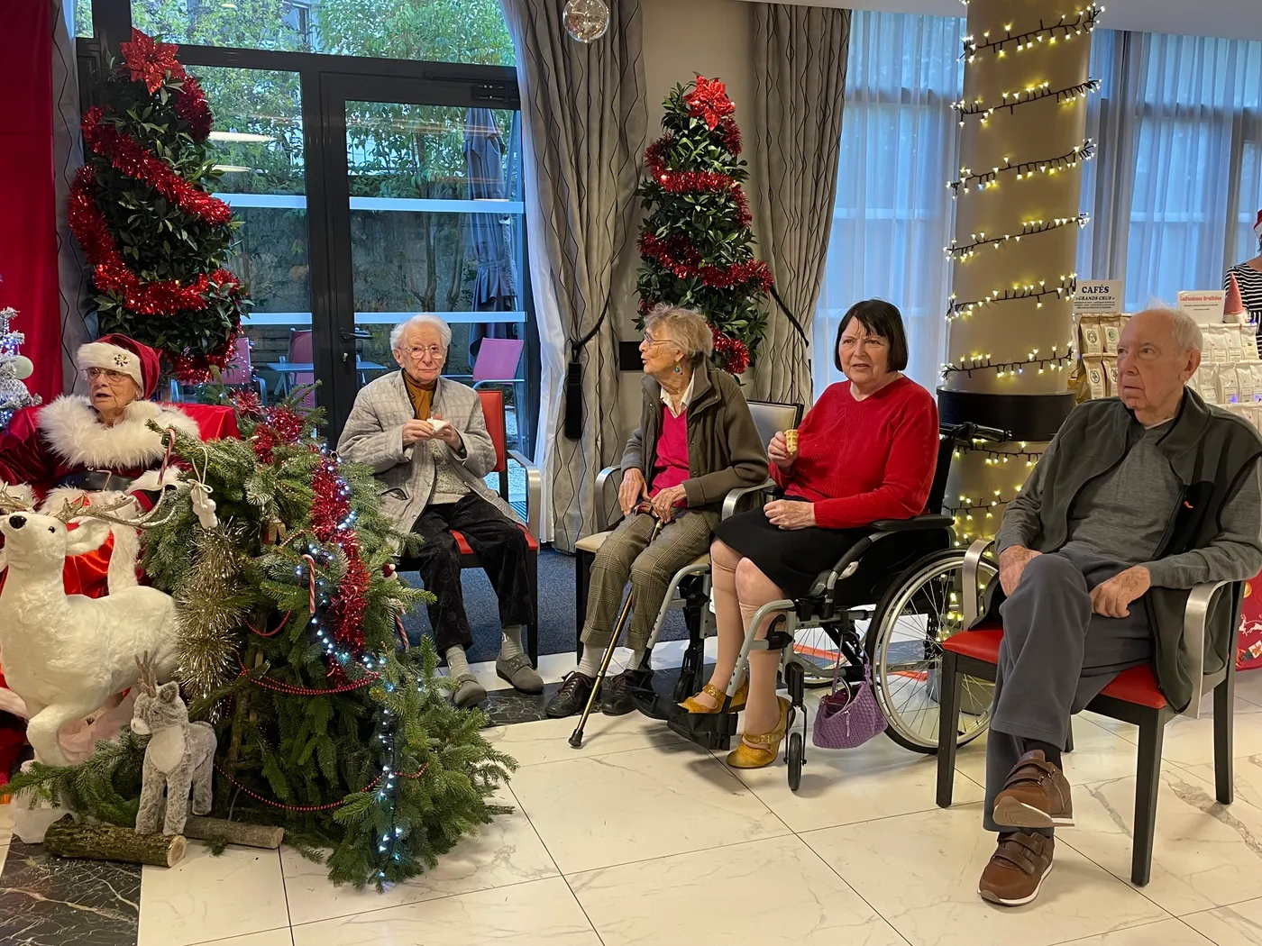 Des résidents assis en rangée écoutent les chants près du sapin de Noël