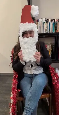 Une membre de l'équipe tient devant son visage une barbe de Père Noël en coton