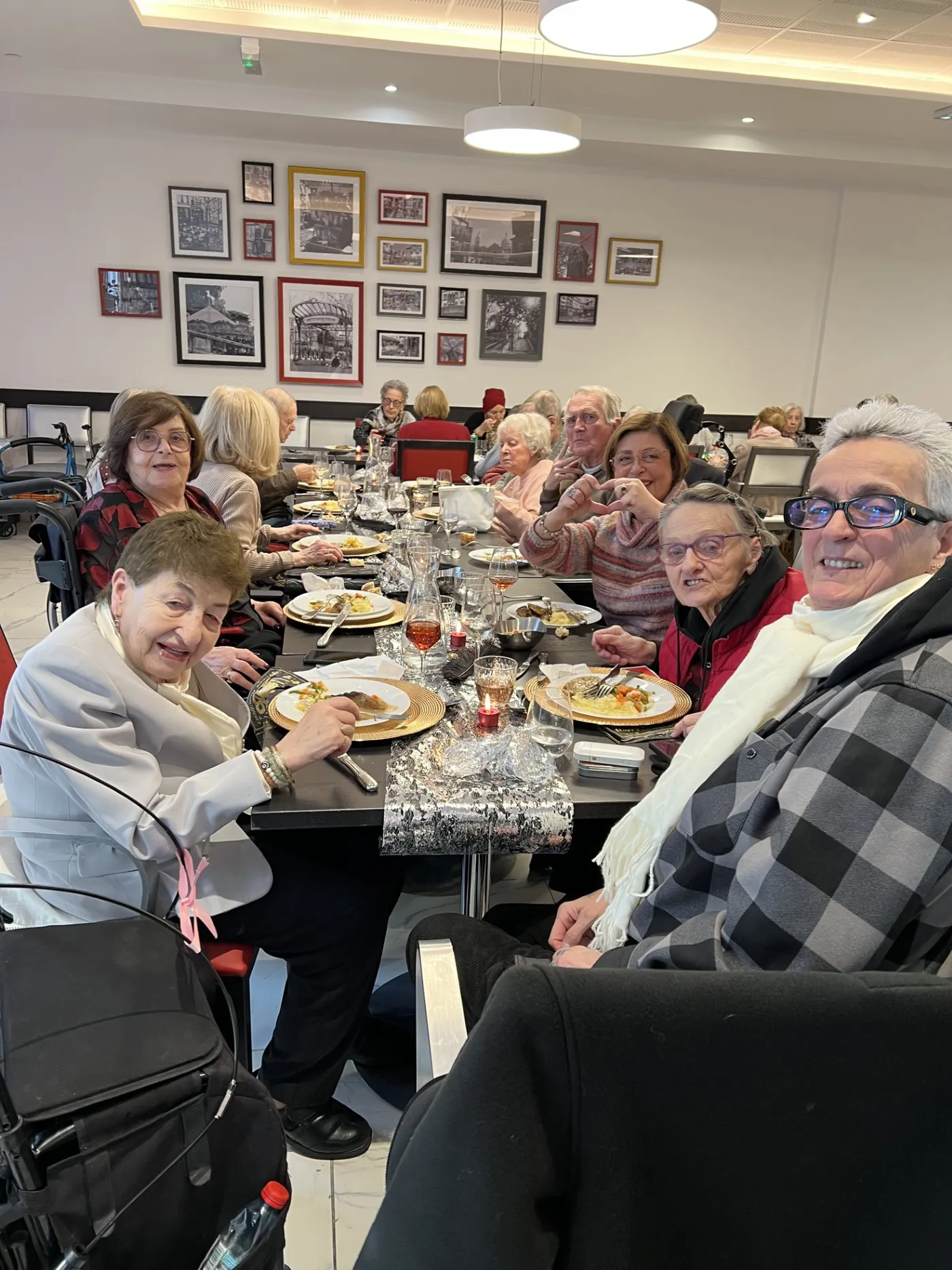 Des résidents attablés lèvent la main et sourient pendant le déjeuner du Nouvel An