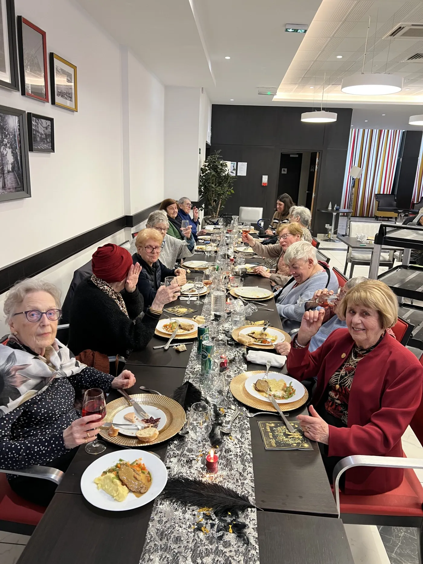 Les convives alignés le long de la table de fête, assiettes et sous-assiettes dorées devant eux