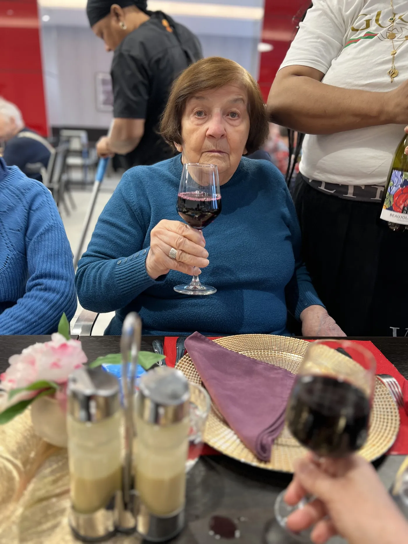 Une résidente lève son verre de vin rouge vers l'objectif