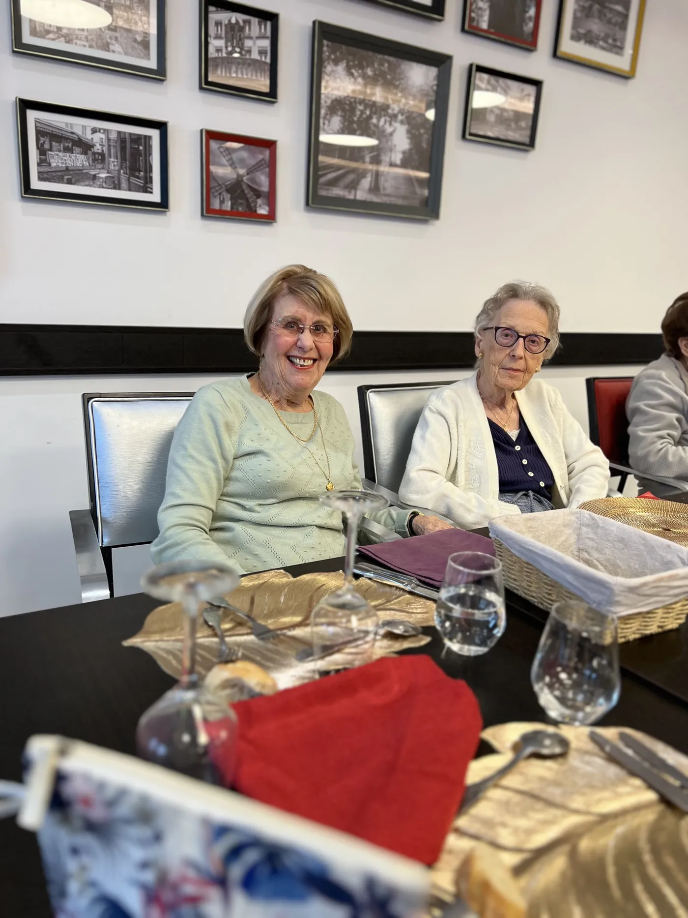 Deux résidentes assises côte à côte à table, des photographies encadrées au mur derrière elles
