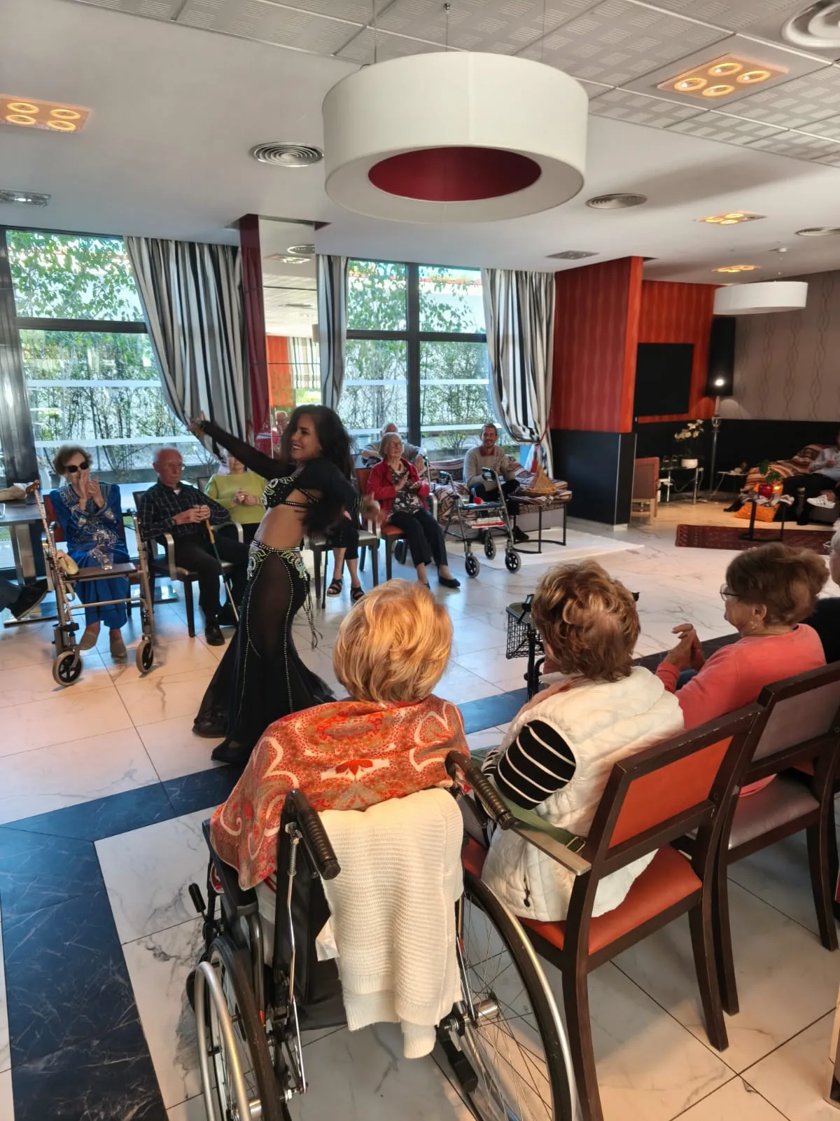 Des résidents suivent depuis leurs fauteuils la prestation d'une danseuse dans le salon