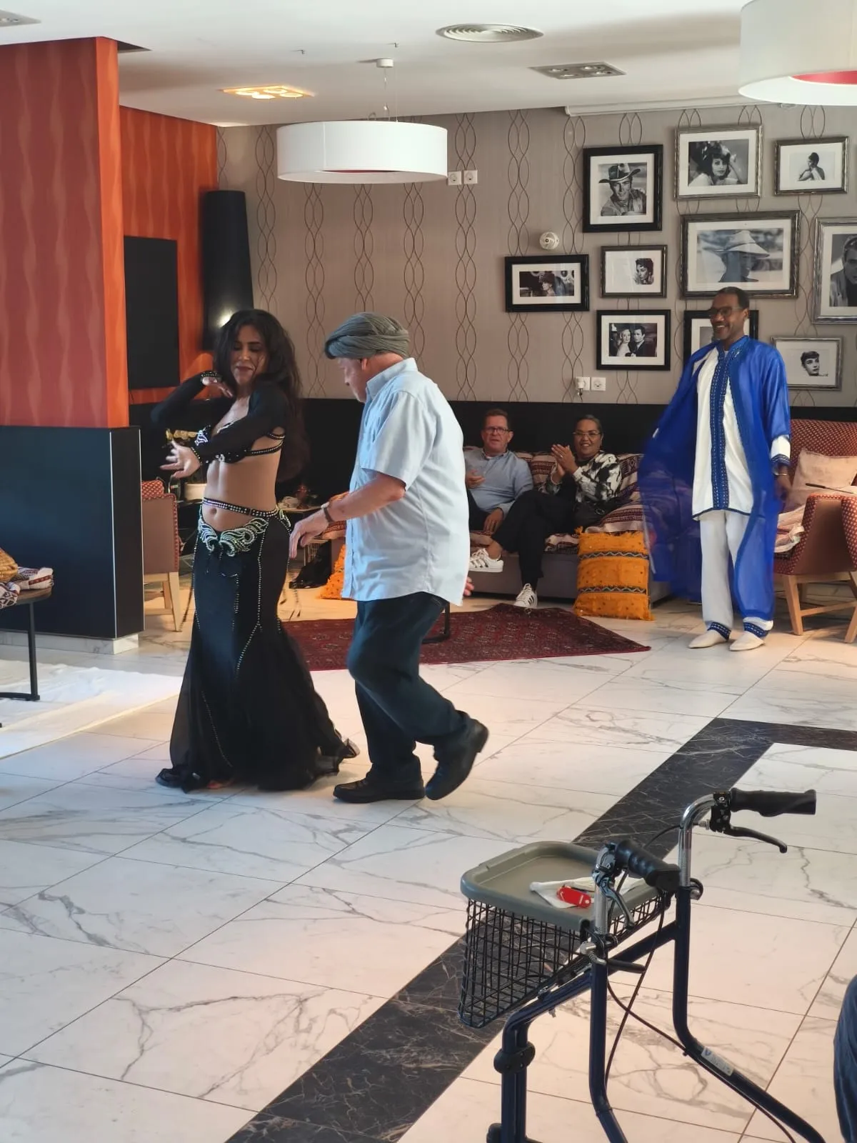 Une danseuse en robe longue entraîne un résident sur la piste