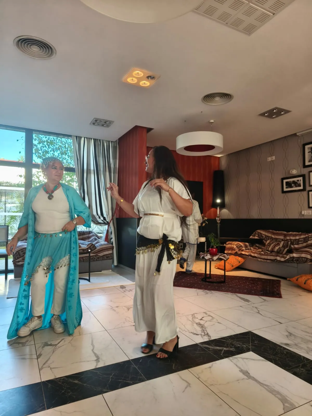 Deux artistes en tenues fluides turquoise et blanche dansent dans le salon