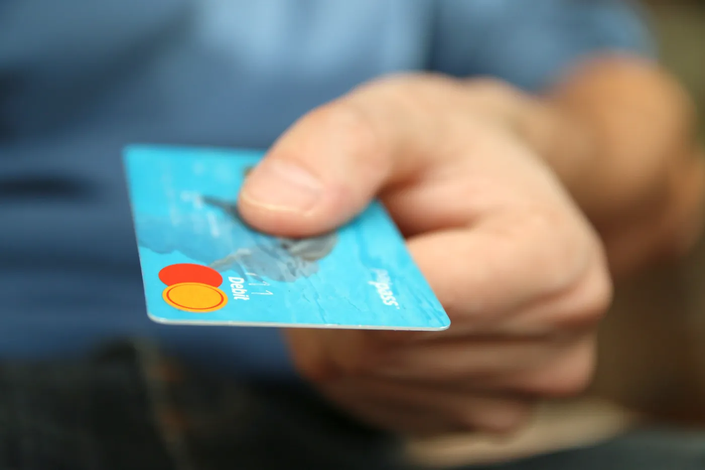 Une main tend une carte bancaire bleue