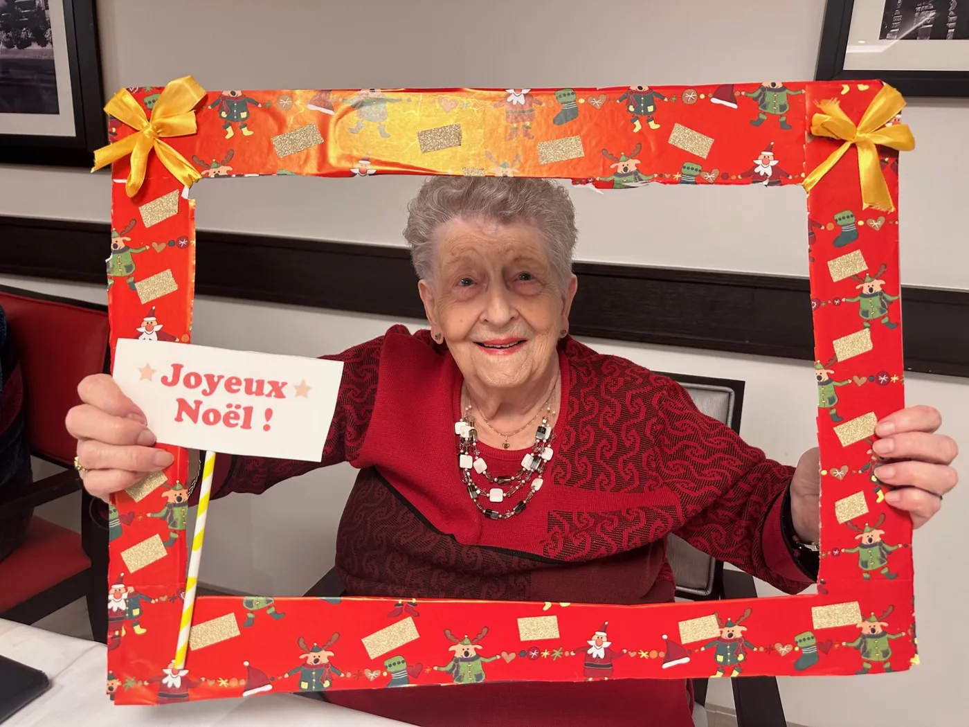 Une résidente brandit un cadre photo fait main portant la carte Joyeux Noël
