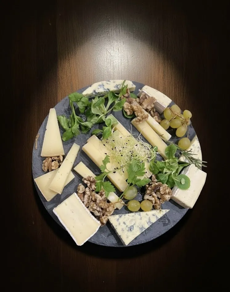 Un plateau d'ardoise garni de fromages, de raisin, de noix et de jeunes pousses