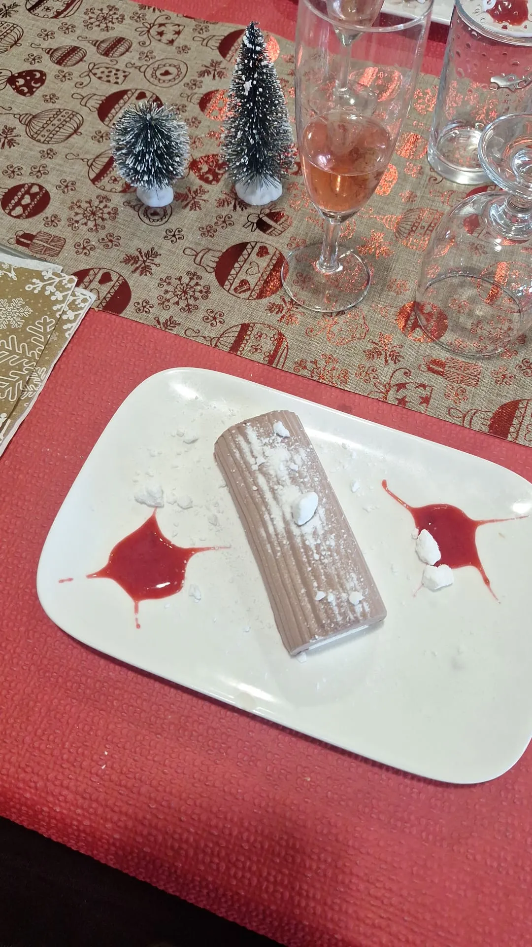 Une part de bûche de Noël au chocolat servie avec un coulis rouge