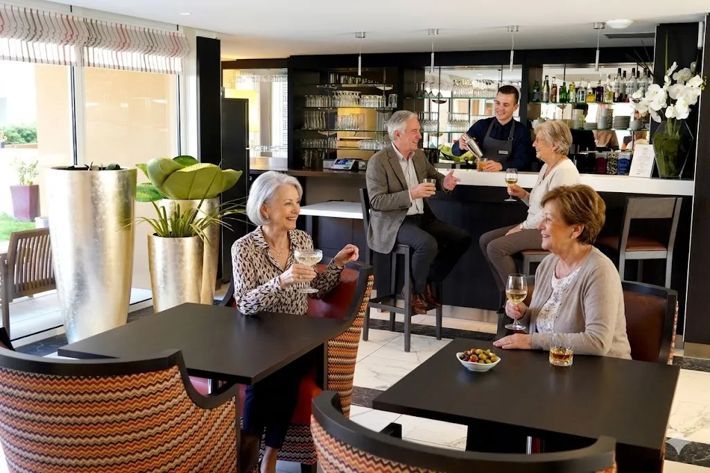 Des résidents attablés aux tables basses près du bar de la résidence