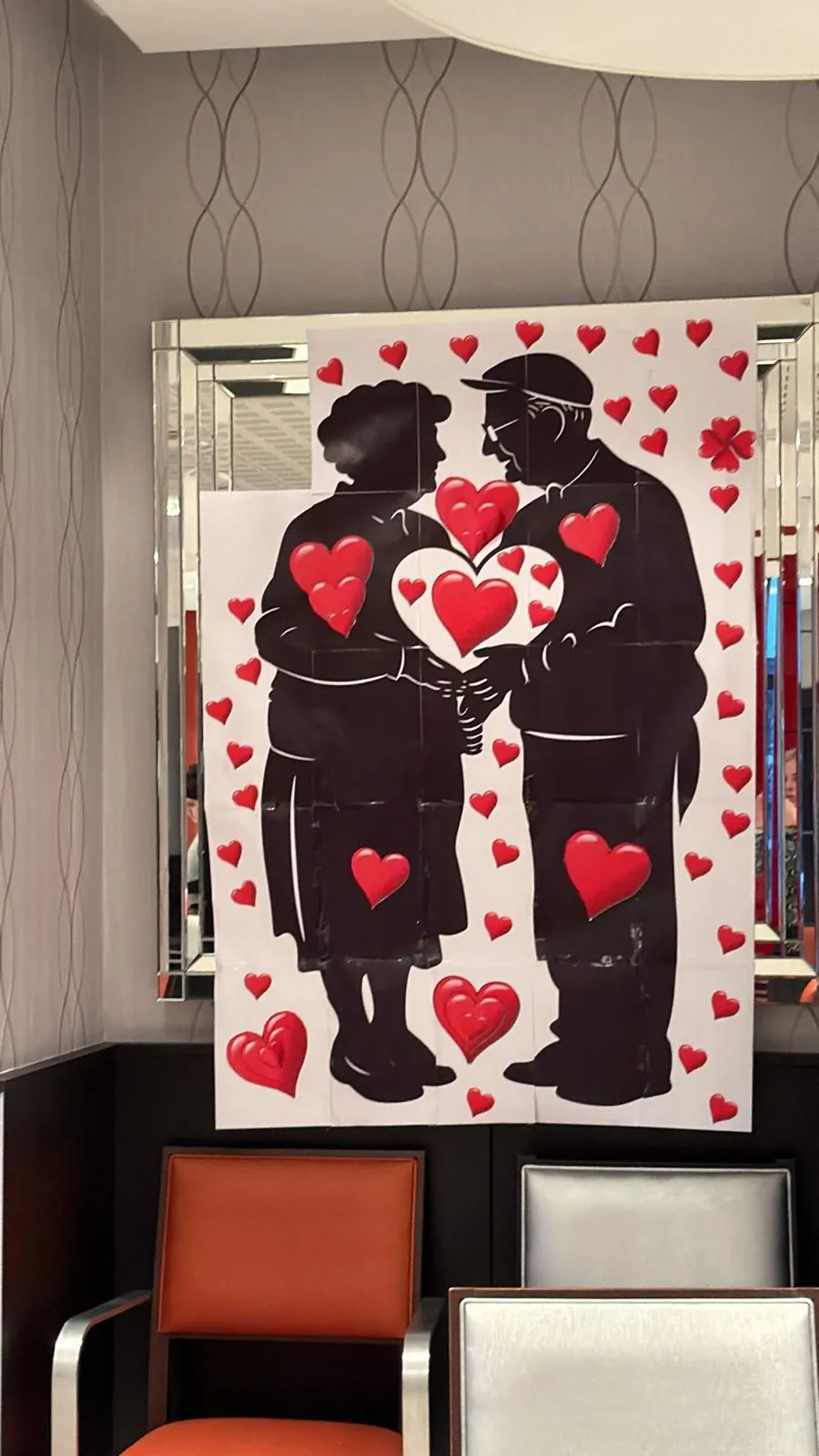 Un tableau représentant un couple âgé entouré de cœurs rouges, accroché au mur du salon