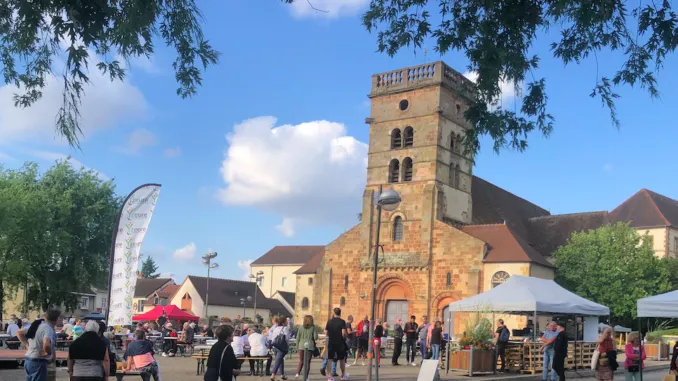 Une foule rassemblée autour des stands et d'un chapiteau devant l'église d'Yzeure
