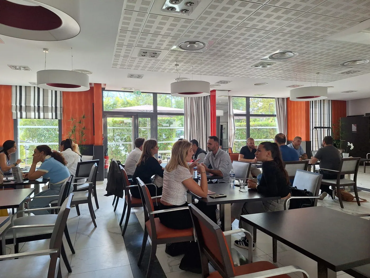 Des professionnels échangent aux tables installées le long des baies vitrées de la salle à manger