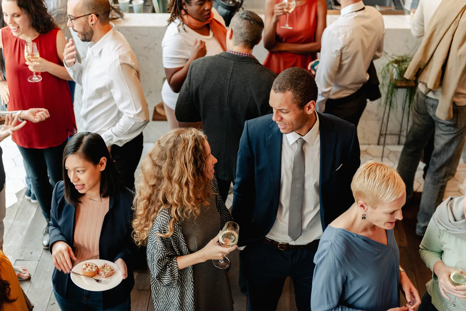 Des professionnels échangent debout, un verre à la main, lors d’une rencontre conviviale.