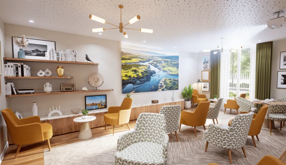 Salon-bibliothèque lumineux d’une résidence OBEO : fauteuils jaunes et à motifs, étagères garnies et grande fresque de paysage