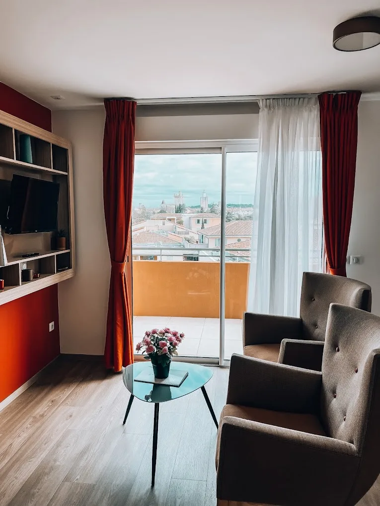 Séjour d’un appartement d’Uzès ouvert par une baie vitrée sur le balcon et les toits de tuiles de la vieille ville